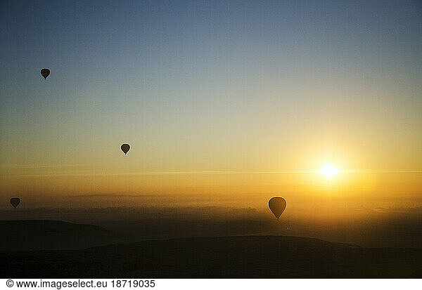 Hot air balloons fly over the Sahara desert during sunrise