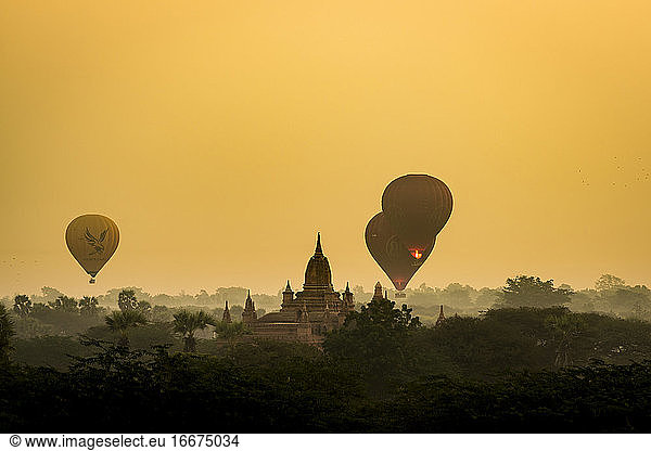 Hot air balloons flying near pagoda during sunrise  UNESCO  Bagan  Myanmar