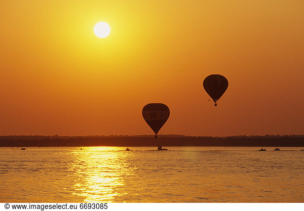 Hot Air Balloons Over Water at Sunset