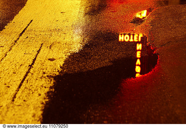 Hotel sign reflected in puddle at night