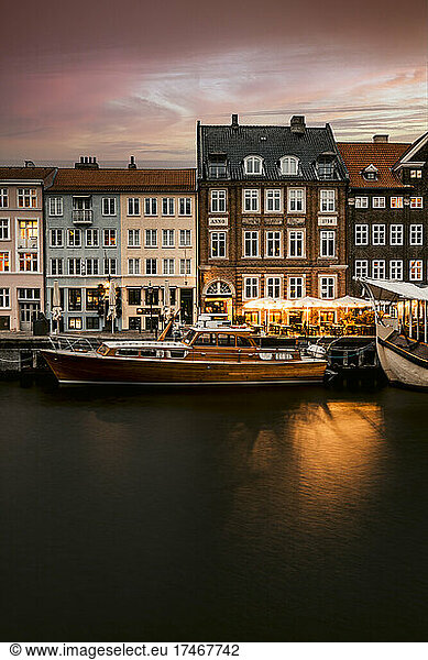 Houses by boats moored in Nyhavn canal at dusk  Copenhagen  Denmark