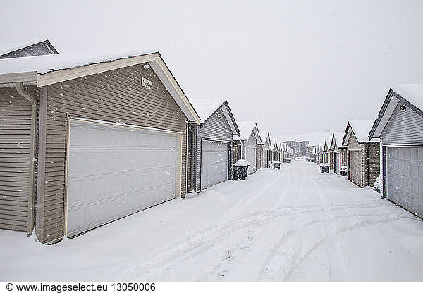 Houses in row against clear sky during snowfall