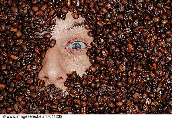 Human face buried in roasted coffee beans