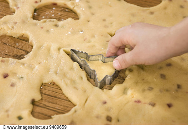 Human hand cutting dough with cutter for cookies  close up