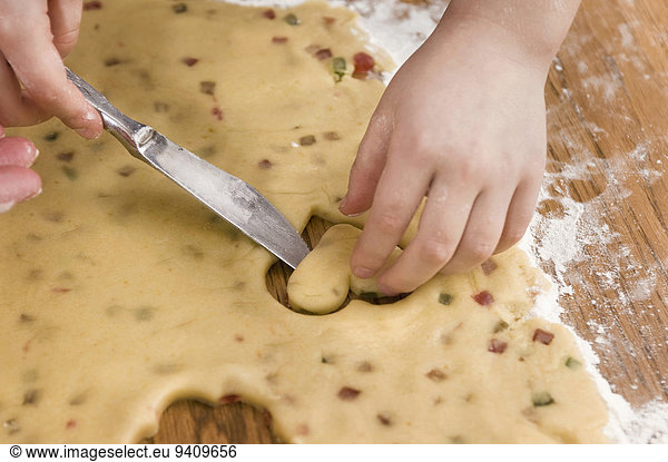 Human hand cutting dough with knife for cookies  close up