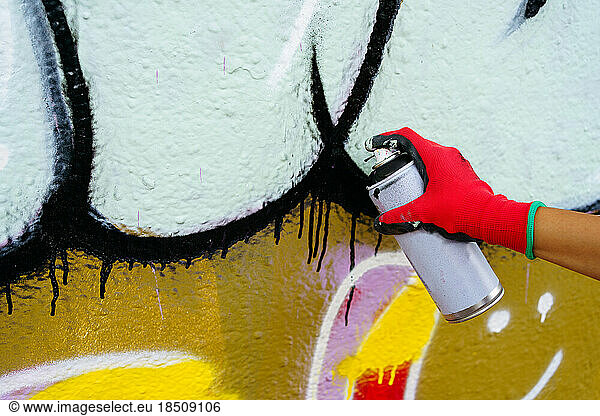 Human hand in red glove drawing graffiti on the wall