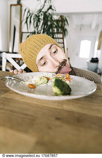 Hungry man licking plate with broccoli