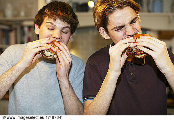 Hungry teenage boys eating hamburgers