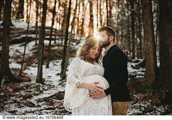 Husband and pregnant wife in the forest on a snowy sunny winter day