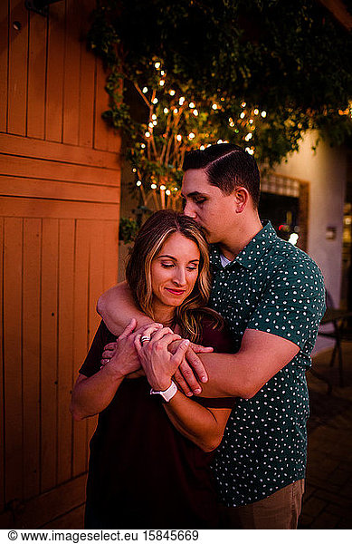 Husband and Wife Embrace as Husband Kisses Wife on Head
