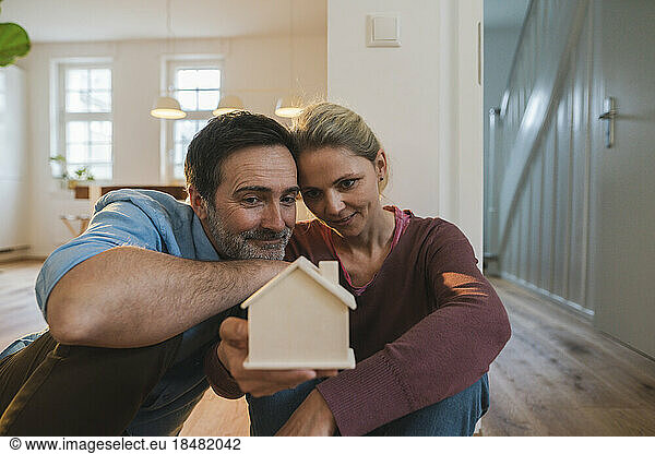 Husband and wife looking at house model sitting at home