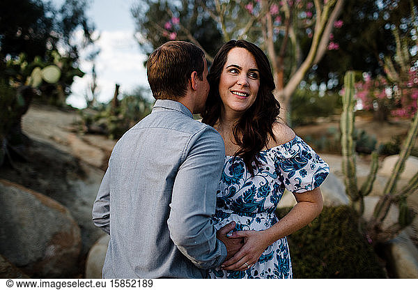 Husband Hugging Pregnant Wife as She Smiles