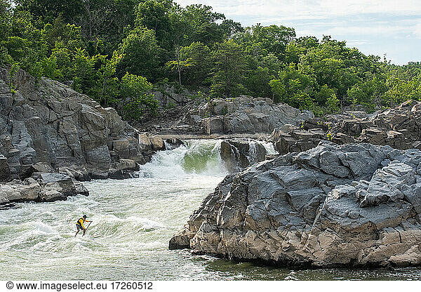 Ian Brown stand up paddle surfs challenging whitewater below Great Falls of the Potomac River  border of Maryland and Virginia  United States of America  North America