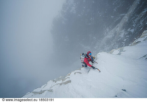 Ice climber climbing steep ice wall in winter