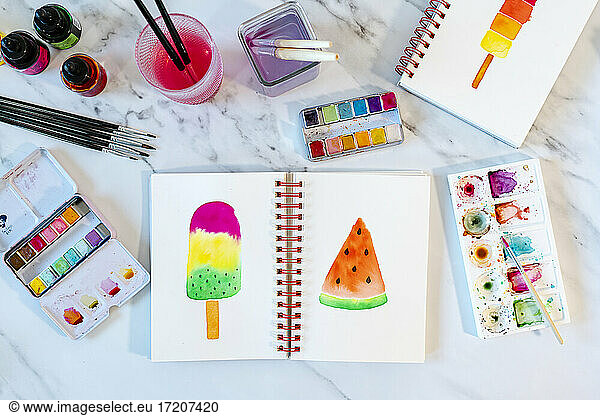 Ice cream bar and watermelon slice painted in book on marble table