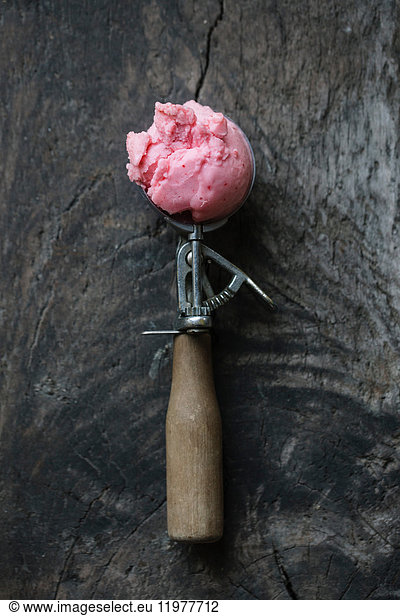 Ice cream in ice cream scoop on wooden surface