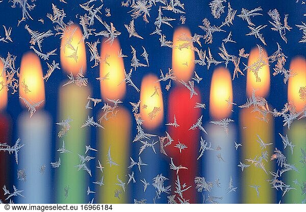 Ice flowers on glass pane in candlelight