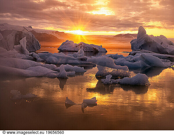 Icebergs floating in Jokulsarlon glacier lagoon lake at sunset.