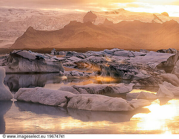 Icebergs floating in Jokulsarlon glacier lagoon lake at sunset.