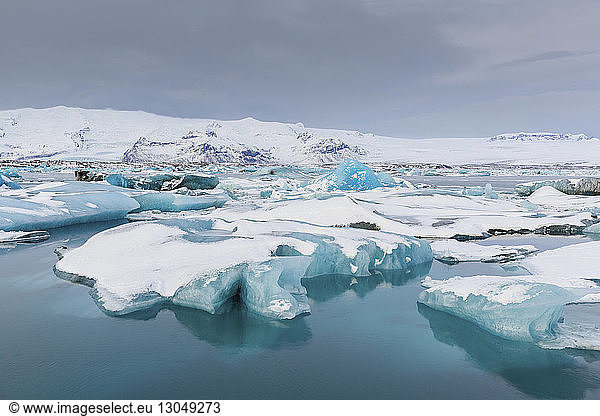 Icebergs in lake against sky during winter
