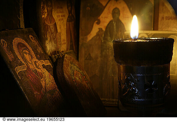 Icons and a lit candle inside a roadside  religious shrine. Crete. Greece