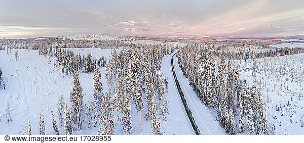 Icy snow covered winter road in the Arctic Circle at sunset in Lapland  Finland