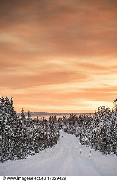 Icy snow covered winter road in the Arctic Circle at sunset in Lapland  Finland