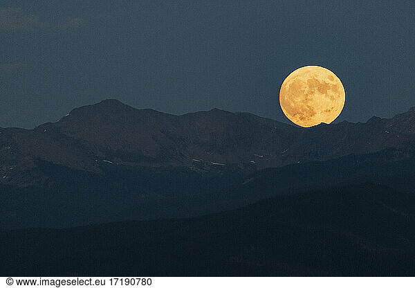 Idyllic shot of full moon over mountain range against clear sky at dusk