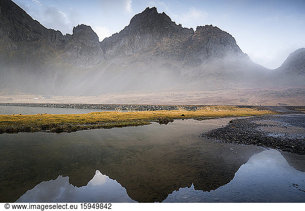 Idyllic view of mountain range reflecting in water against sky at Hvalnes Nature Reserve Beach  Iceland