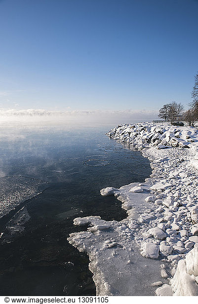 Idyllischer Anblick eines zugefrorenen Sees gegen den Himmel bei nebligem Wetter