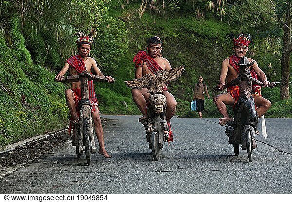 Ifugao tribesmen on wooden scooters and tricycle.