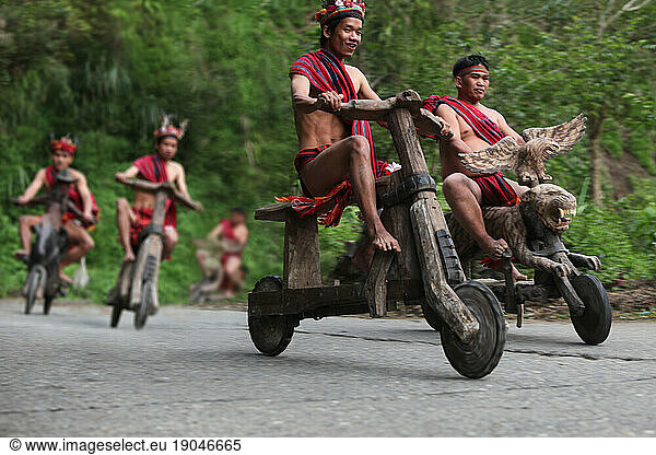 Ifugao tribesmen racing on wooden scooters.
