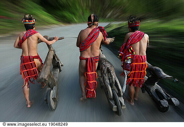 Ifugao tribesmen shoving wooden scooters.