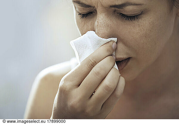 Ill woman blowing nose with tissue paper