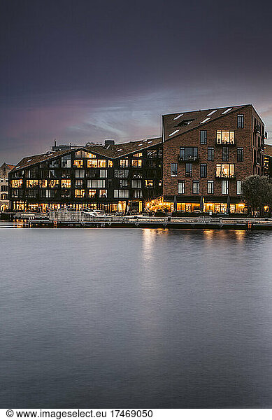 Illuminated buildings by canal at dusk  Copenhagen  Denmark