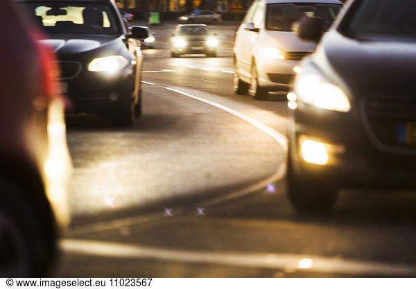 Illuminated headlights of cars on road