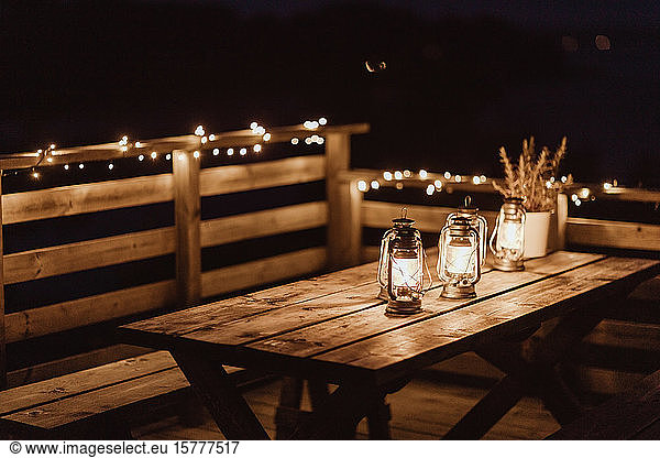 Illuminated lanterns on empty table at restaurant during night