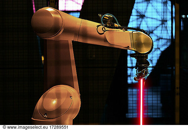 Illuminated robotic arm with laser at factory