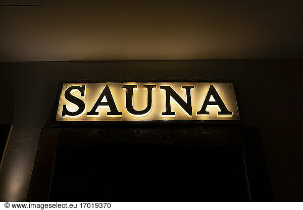 Illuminated sauna sign in dark at health spa