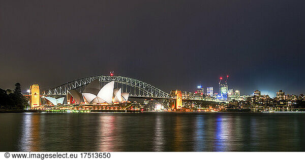 Illuminated Sydney Harbor Bridge and buildings over river against sky at night  Australia
