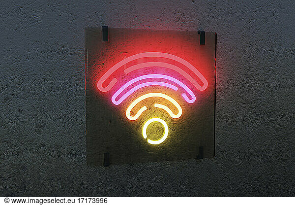 Illuminated WiFi sign against black wall