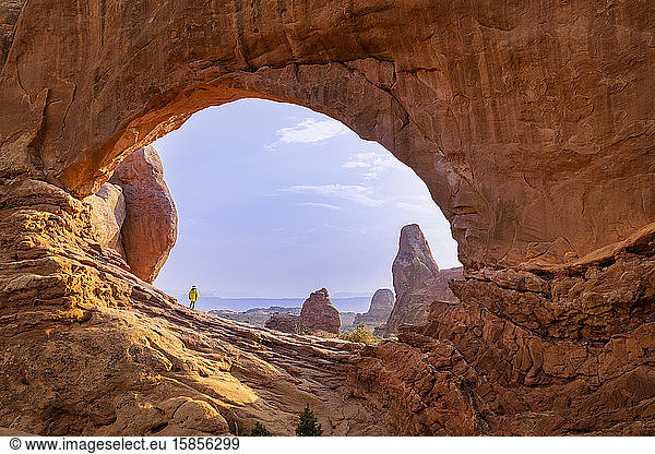 Im Nordfenster eingerahmte Wanderin vor blauem Himmel in Arches