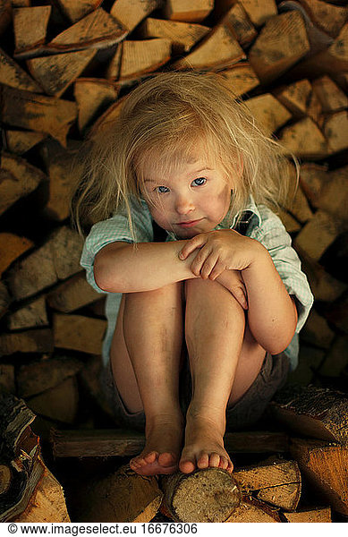 Image of a grimy child sitting on the wood.