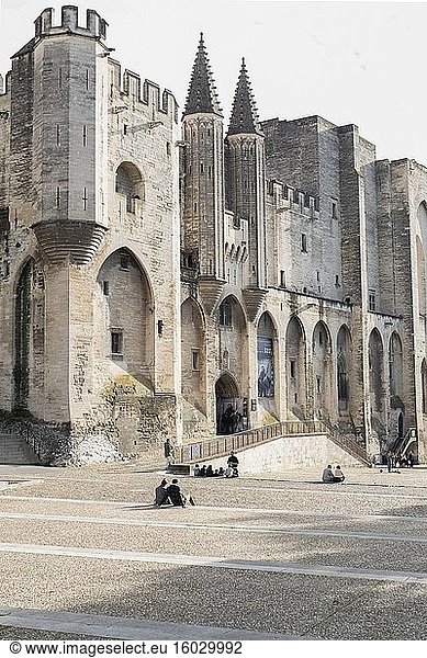 Imposante  mit Zinnen versehene Türme und Befestigungsanlagen des Papstpalastes  darunter Gruppen von sitzenden Schulkindern  Avignon  Provence  Frankreich.