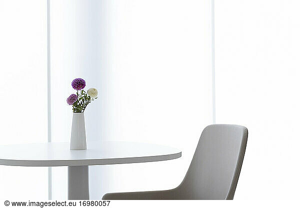 in a refined style  a table with a privatvase containing three flowers