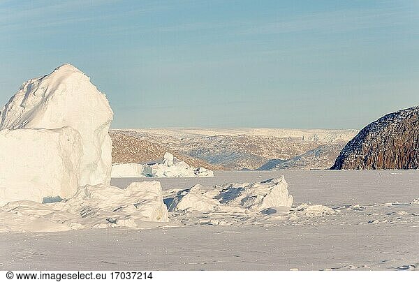 In das Meereis des Uummannaq-Fjordsystems eingefrorene Eisberge im Winter im Nordwesten Grönlands  im Hintergrund die Eiskappe. Nordamerika  Grönland  dänisches Gebiet.