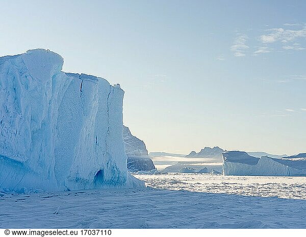 In das Meereis des Uummannaq-Fjordsystems eingefrorene Eisberge im Winter im Nordwesten Grönlands  im Hintergrund die Insel Uummanaq. Nordamerika  Grönland  dänisches Gebiet.
