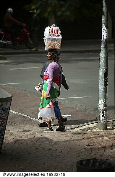 In die südafrikanische Flagge gehüllte Afrikanerin  die Lebensmittel auf dem Kopf trägt. Johannesburg  Südafrika