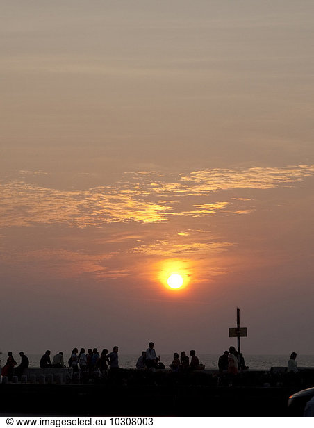 India  Mumbai  Ppeople sitting at beach promenade  watching sunset