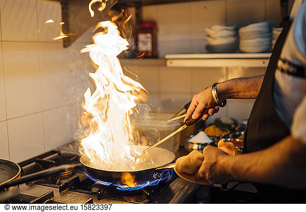 Indian chef flambing food in restaurant kitchen  close up